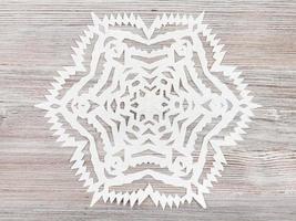 sneeuwvlok gesneden van papier Aan licht bruin tafel foto