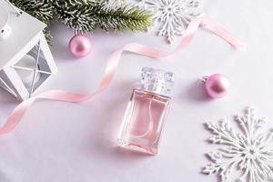 een elegant fles van vrouwen parfum Aan een wit satijn achtergrond tussen Kerstmis decoraties. naamloos fles. reclame concept. foto