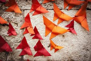 groep van vogelstand origami oranje en rood Aan een muur. horizontaal afbeelding. foto