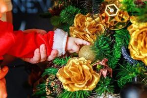 dichtbij omhoog baby handen decoreren Kerstmis boom Aan Kerstmis vooravond Bij huis. jong kind met winter decoratie. gelukkig familie Bij huis. Kerstmis nieuw jaar december tijd voor viering concept. foto