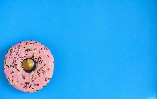roze donut Aan een helder blauw achtergrond proost omhoog, kopiëren ruimte foto
