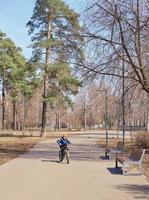 een tiener ritten een fiets in een park met een pijnboom foto