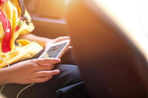 een schoolmeisje op zoek Bij haar telefoon terwijl rijden een privaat auto Aan haar manier huis, levensstijl, onderwijs leven foto