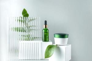 anti-veroudering collageen gelaats serum in groen glas fles en gezicht room Aan wit podium achtergrond met kopiëren ruimte. natuurlijk biologisch kunstmatig schoonheid concept. mockup voor branding foto