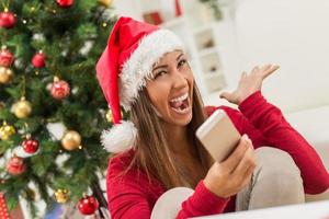 meisje met santa's hoed en slim telefoon foto