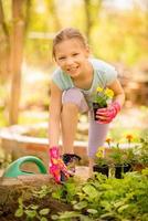 schattig weinig meisje aanplant bloemen foto