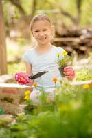 schattig weinig meisje aanplant bloemen foto