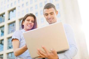 collega's met laptop in voorkant van bedrijf foto