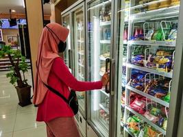 probolinggo, Indonesië. nov. 06,2022 - een vrouw vervelend een hijab is boodschappen doen Bij de mini markt foto