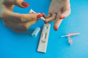 lekke band van de vinger met een lancet. snel bloed testen. test strip voor de diagnose van coronavirus. een laten vallen van capillair bloed voor de detectie van immunoglobulinen foto