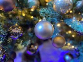 groen takken van een pluizig Kerstmis feestelijk nieuw jaar boom met speelgoed in ballen en helder gloeiend licht bollen en slingers, achtergrond foto
