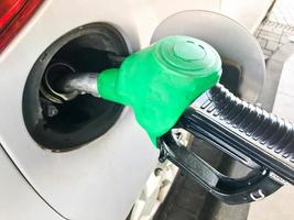 groen vulling pistool zit vast in de gas- tank van een auto Bij een gas- station. de werkwijze van vulling de auto met brandstof, benzine, diesel foto