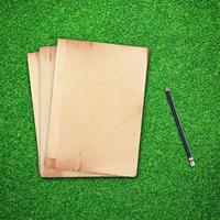 potlood en oud boek Aan groen gras achtergrond foto