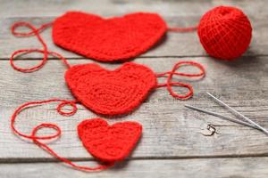 drie rood gebreid harten Aan een grijs houten achtergrond, symboliseert liefde en familie. familie relatie, obligaties. foto