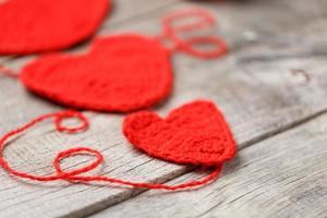 drie rood gebreid harten Aan een grijs houten achtergrond, symboliseert liefde en familie. familie relatie, obligaties. foto