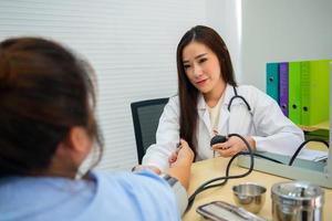 Aziatisch vrouw dokter gebruik kwik bloed druk naar bepalen geduldig bloed druk. foto