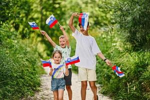 drie kinderen houden Sloveens vlaggen in triglav nationaal park, Slovenië. foto