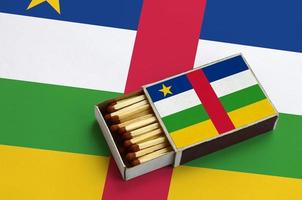 centraal Afrikaanse republiek vlag is getoond in een Open luciferdoosje, welke is gevulde met wedstrijden en leugens Aan een groot vlag foto
