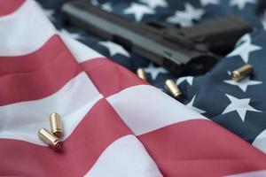 9 mm kogels en pistool liggen Aan gevouwen Verenigde staten vlag foto