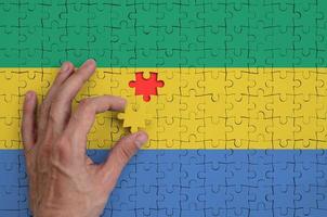 Gabon vlag is afgebeeld Aan een puzzel, welke de man's hand- voltooit naar vouwen foto