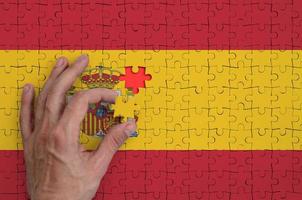 Spanje vlag is afgebeeld Aan een puzzel, welke de man's hand- voltooit naar vouwen foto