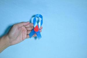 top visie blauw lint bewustzijn met rood bloed laten vallen in Mens handen geïsoleerd Aan een blauw achtergrond. 14 november, wereld diabetes dag. copyspace foto