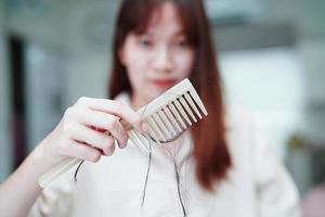 aziatische vrouw heeft een probleem met lang haarverlies, hecht zich aan de kamborstel. foto