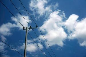 elektrisch pool macht lijnen uitgaand elektrisch draden tegen Aan wolk blauw lucht. foto