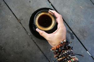 vrouw hand- Holding robusta americano heet koffie Aan glas. foto