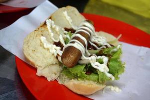 Indonesië lokaal hotdog. gebraden rundvlees, worst, sesam brood, sla, mayonaise en saus. hotdog maken werkwijze. straat voedsel. foto