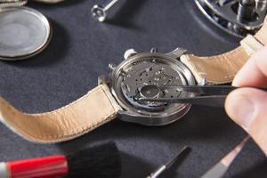 horlogemaker met een pincet op horloge foto