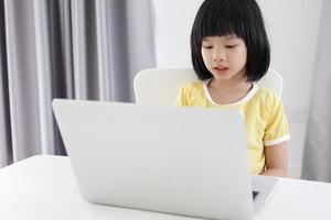 weinig Aziatisch meisje leerling studie online gebruik makend van laptop computer Bij huis foto