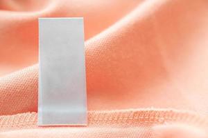blanco wit wasserij zorg kleren etiket Aan roze kleding stof structuur achtergrond foto