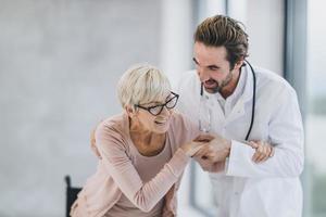 dokter zorgzaam een senior vrouw rolstoelgebonden geduldig in de ziekenhuis gang foto