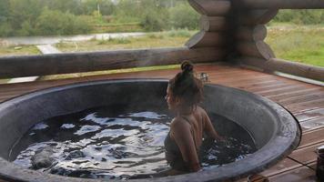 vrouw ontspannende in heet bad buitenshuis, genieten van thermisch spa foto