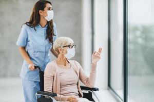 jong verpleegster zorgzaam een senior vrouw rolstoelgebonden geduldig foto