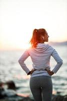 vrouw genieten van zomer zonsondergang en ontspannende gedurende opleiding in de buurt de zee foto