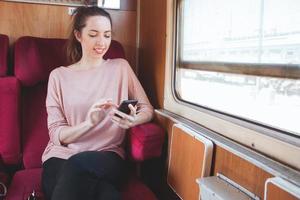 jonge lachende vrouw met behulp van smartphonet reizen op de trein