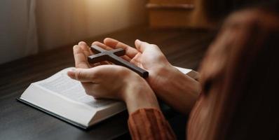 vrouw zittend en aan het studeren de geschriften.de houten kruis in de handen. christen onderwijs concepten de heilig geschriften Open foto