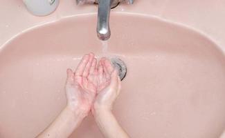 het wassen handen met zeep in badkamer foto