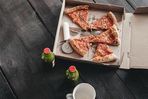 Frisdrank en peperoni worst pizza in een doos Aan een donker houten vloer, top visie foto