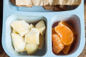 schooljongen lunch doos Aan houten achtergrond.appel,mandarijn in lunchbox foto