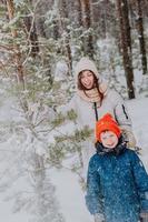 mam en zoon Speel sneeuwballen in de winter Woud. mam wandelingen met haar zoon in een sneeuwval in de Woud. gelukkig winter vakantie met sneeuw. winter wandelingen in de Woud. foto