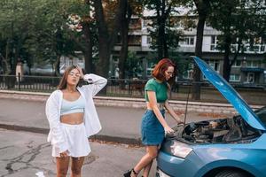 twee Dames met gebroken auto Aan de weg. Open kap foto