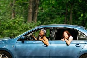 twee vriendinnetjes dwaas in de omgeving van en lachend samen in een auto foto