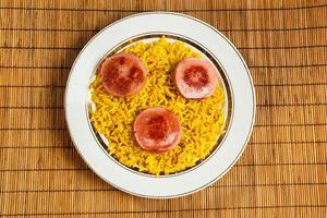 geel rijst- Aan een bord met gebakken worst. foto