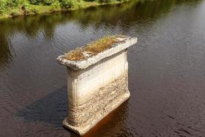 oud brug ondersteuning staat in rivier, ondersteuning van de vernietigd brug foto