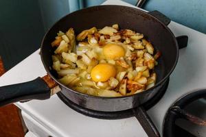 gebakken aardappelen met ei in een frituren pan, voedsel bachelor opleiding, gekookt door een mannetje foto