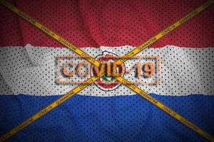 Paraguay vlag en covid-19 postzegel met oranje quarantaine grens plakband kruis. coronavirus of 2019-ncov virus concept foto