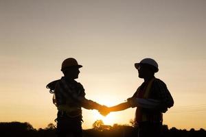 ingenieur en arbeider handdruk Bij bouw plaats silhouet foto